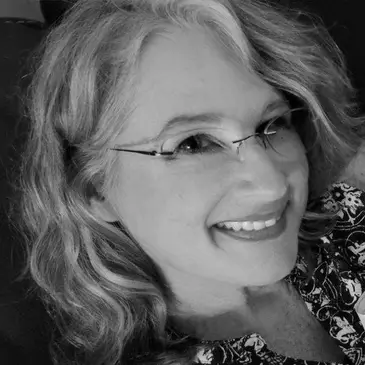Smiling woman with glasses and curly hair.